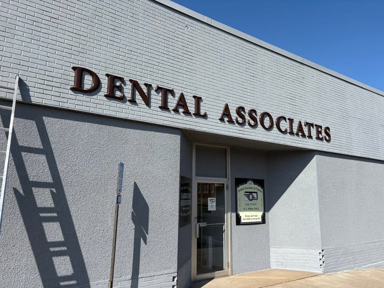 Exterior of Dental Associates office building with white brick facade and dark entrance door under clear blue sky