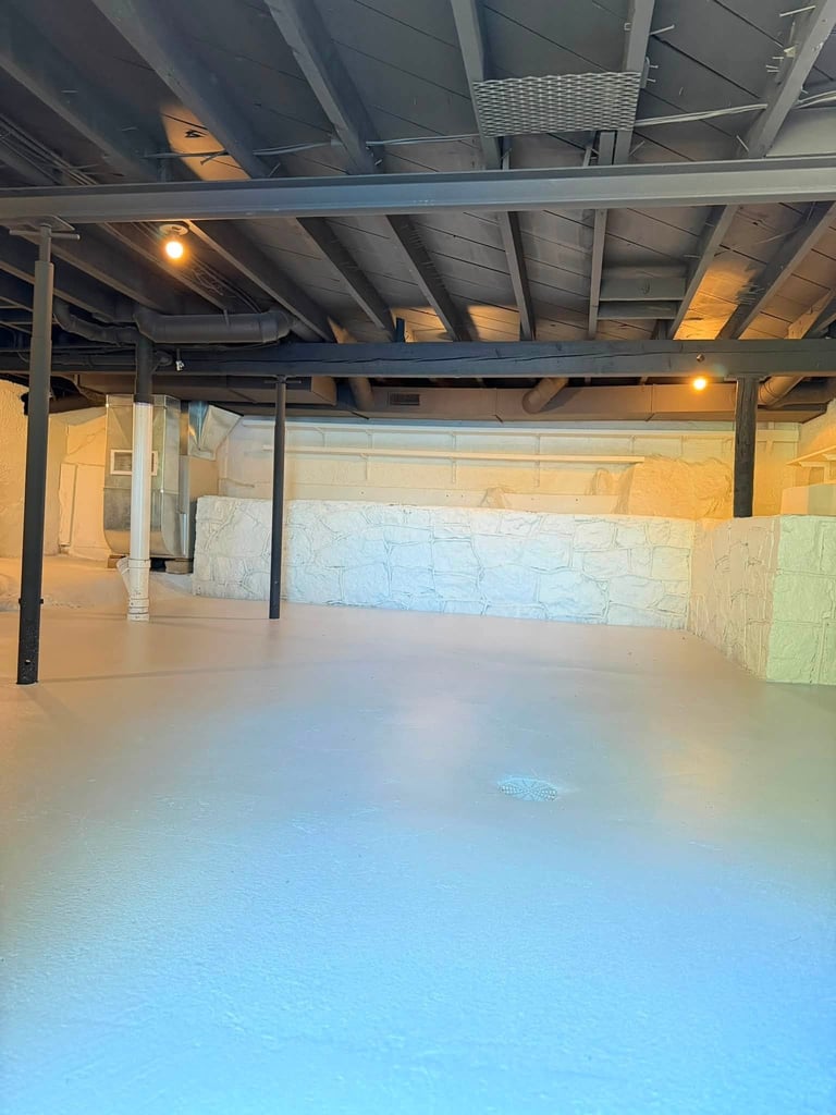 Empty warehouse or industrial space with light blue painted concrete floor, exposed steel beams, and warm overhead lighting